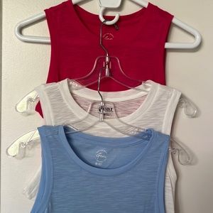 Bundle of three sleeveless t shirts, one light blue, one white and one fuchsia